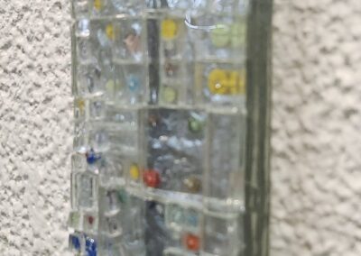 Multicolored glass mosaic on textured wall.