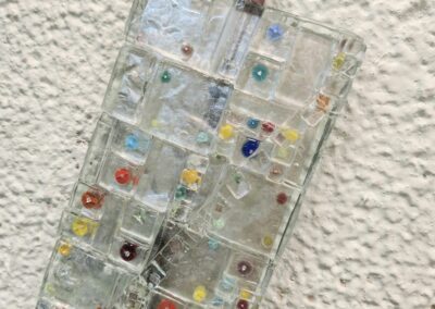 Colorful mosaic glass art on textured wall.