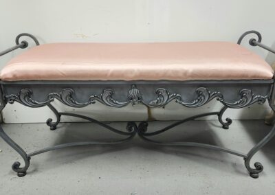 Ornate bench with pink cushioned seat.