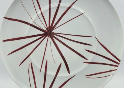 White plate with red abstract leaf design.