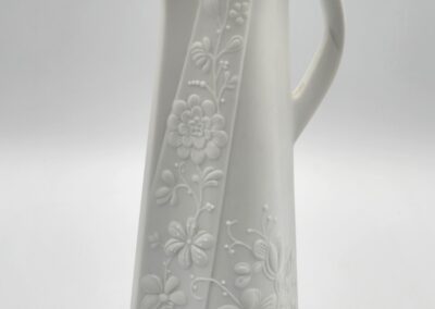 White floral-embossed ceramic pitcher with handle.