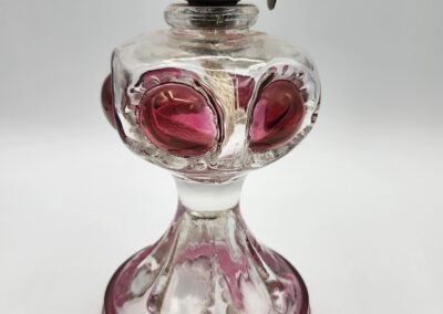 Antique glass oil lamp with pink accents.