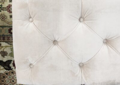 Tufted beige headboard on patterned carpet.