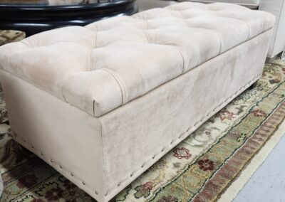 Tufted beige ottoman on patterned rug.