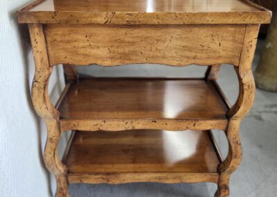 Wooden three-tiered table with curved legs.