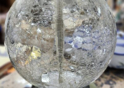 Glass lamp with cracked globe on table.