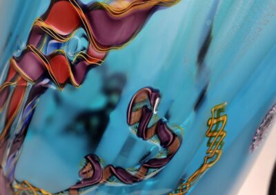 Colorful abstract pattern on blue glass vase.