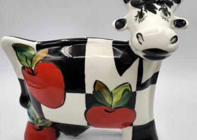 Ceramic cow with red apple design.