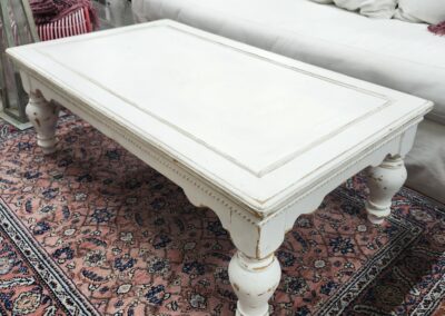 White wooden coffee table on patterned rug.