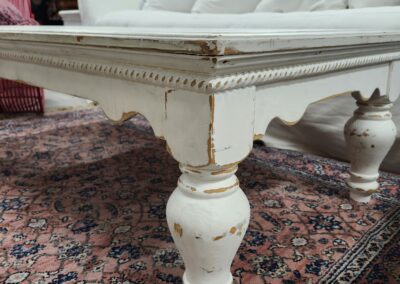 White vintage coffee table on patterned rug.