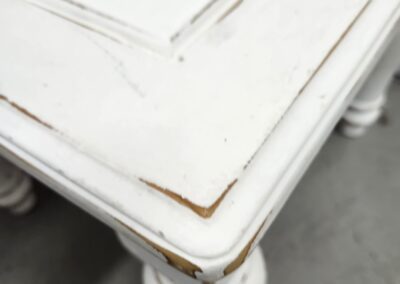 Distressed white wooden table corner detail.