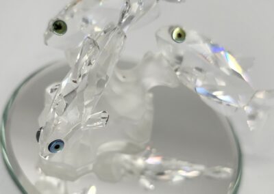 Crystal fish figurines on a reflective base.