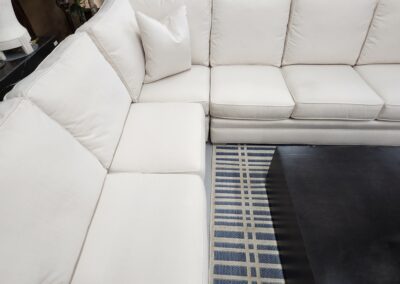 White sectional sofa with blue-striped rug.