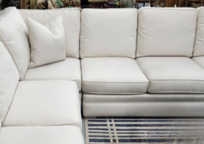 White sectional sofa with striped rug.