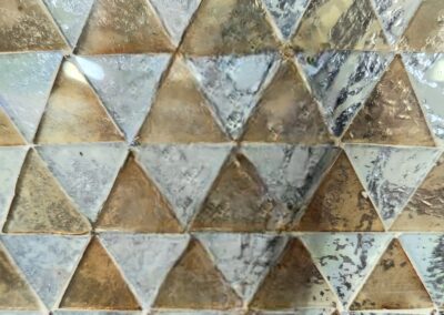 Reflective triangular tile mosaic with metallic finish.