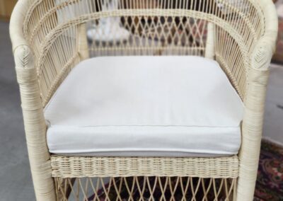 Wicker chair with white cushion on rug.
