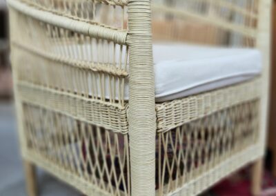 Wicker chair with cushion on patterned rug.