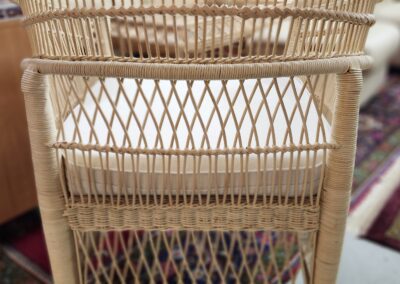 Wicker chair with white cushion, colorful rug.