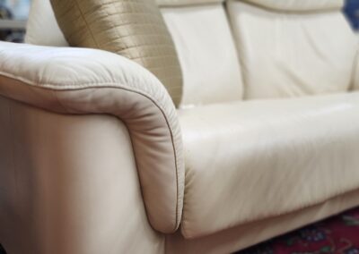 Cream sofa with cushion on patterned rug.