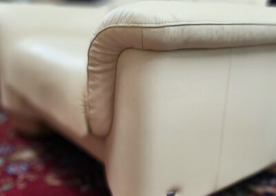 Cream sofa corner on patterned red carpet.