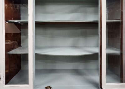 Empty white display cabinet with glass doors.