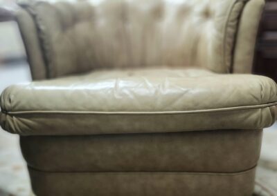 Cream leather armchair with tufted back.