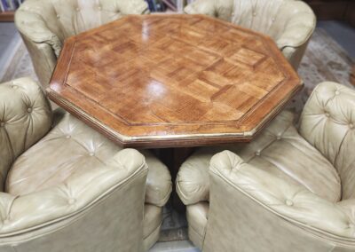 Octagonal wooden table with beige chairs.