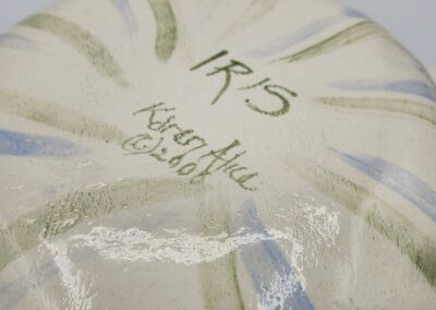 Ceramic base with artist signature and design.