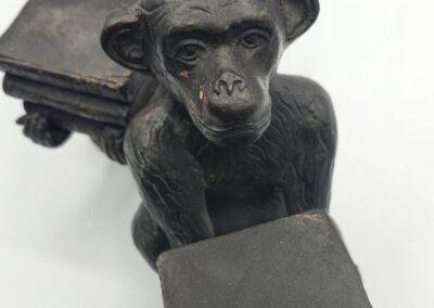 Monkey statues holding books, white background.
