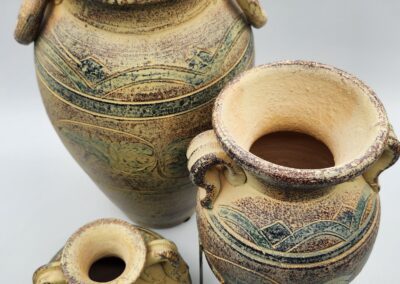 Three decorative ceramic pots with handles.