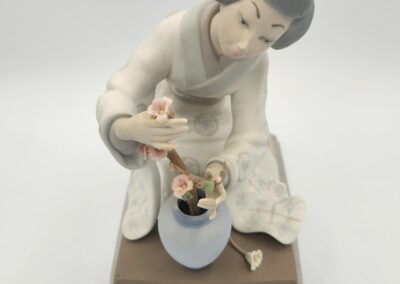 Ceramic figurine of woman arranging flowers.