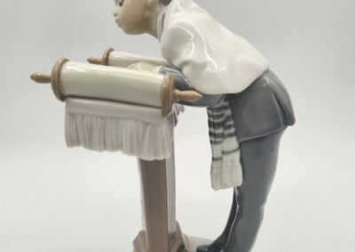 Boy reading scroll on stand figurine.