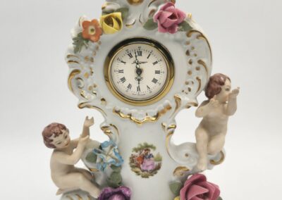 Ornate porcelain clock with cherubs and flowers.