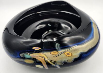 Black ceramic bowl with abstract colorful design.