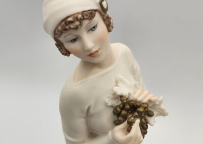 Vintage porcelain figurine holding flowers, wearing hat.