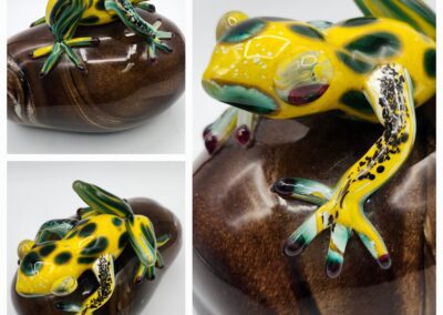 Colorful glass frog on wooden base.