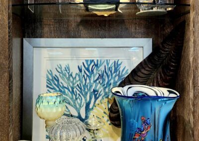 Decorative glass items on wooden display shelf.