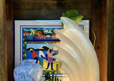 Shelf with decorative glass sculptures and painting.