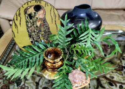 Decorative items on glass table with greenery.