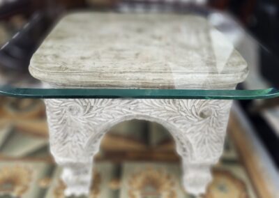 Glass-topped table with ornate carved base.