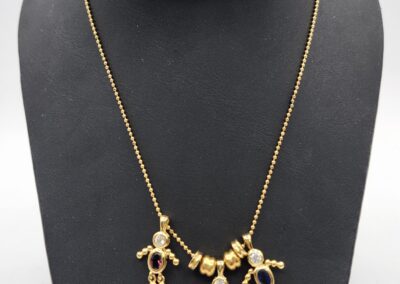 Gold necklace with three doll-shaped pendants.