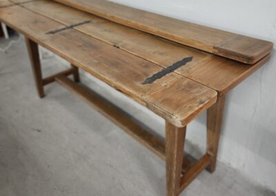 Wooden bench with metal hinges on floor.
