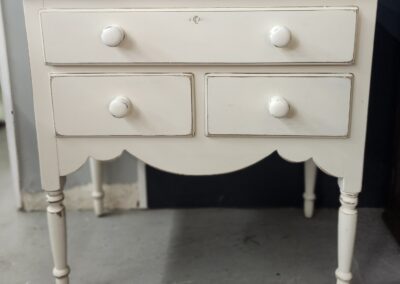 White vintage wooden dresser with four drawers.