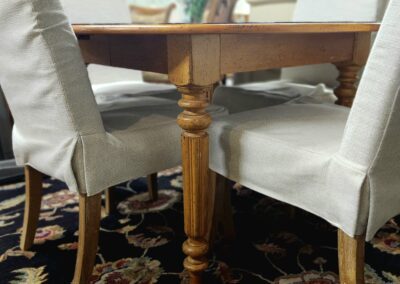 Wooden table and chairs on floral rug.