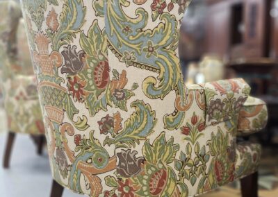 Floral-patterned armchair with wooden legs.