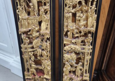 Ornate gold wood carvings in black frames.