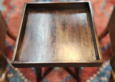Wooden tray table on patterned rug.