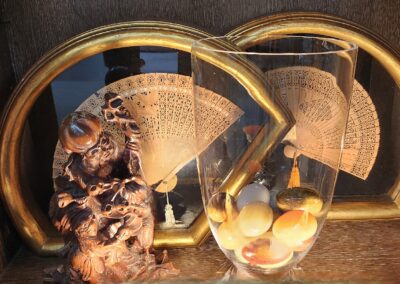 Wooden statue, glass vase, decorative fans displayed.