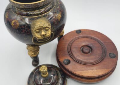 Ornate vase with lid and wooden base.