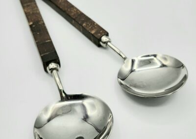 Wood-handled metal salad servers on white background.